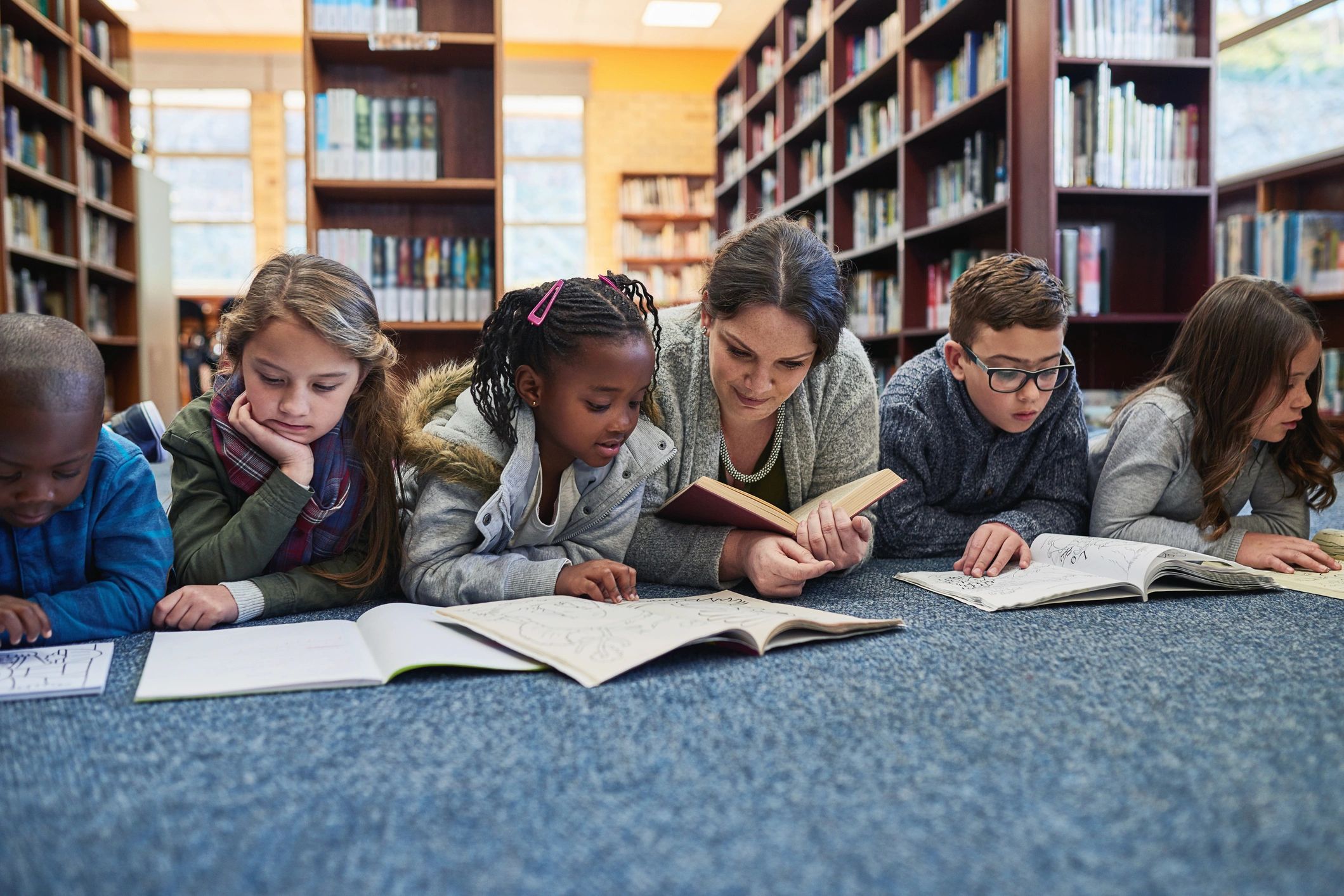 Group of children and teacher in a library learning together